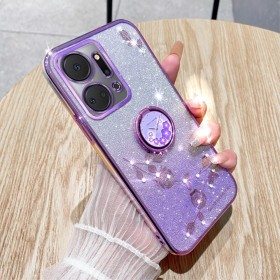 Honor X7A violetti glitter kukka sormuspidike suojakuori puhelimen päällä kädessä, taustalla puupöytä.