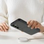 Samsung Galaxy A55 5G musta MagSafe-yhteensopiva suojakuori kädessä, taustalla langaton laturi.
